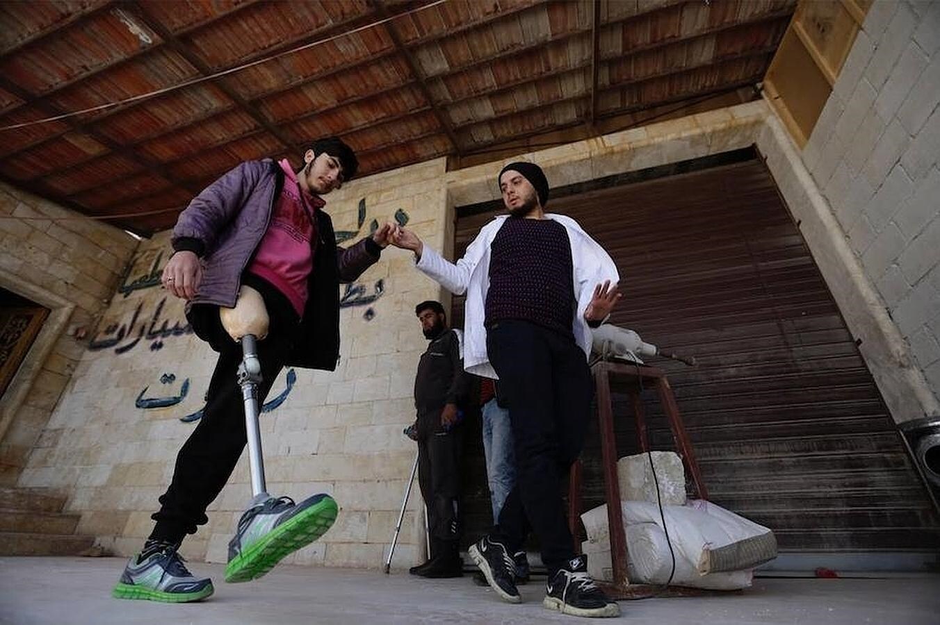 Khamis ayuda a un adolescente mutilado a caminar usando su nueva prótesis