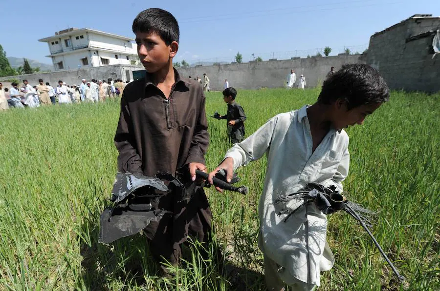 Niños recogen restos en el lugar donde cayó un helicóptero en las cercanías del escondite de Bin Laden el 3 de mayo de 2011