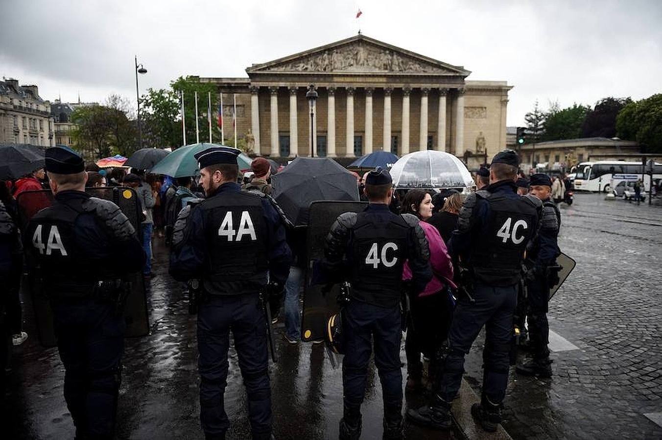 Manifestantes se enfrentan a la policía antidisturbios mientras protestan contra el artículo 49.3 frente a la Asamblea Nacional, en París. 