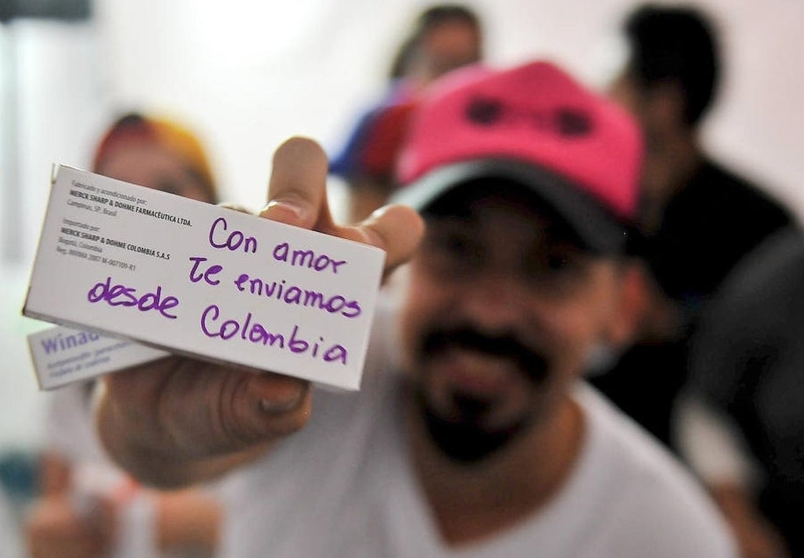 Un hombre muestra un mensaje escrito en una de las cajas de medicamento que han sido donados en la colecta. 