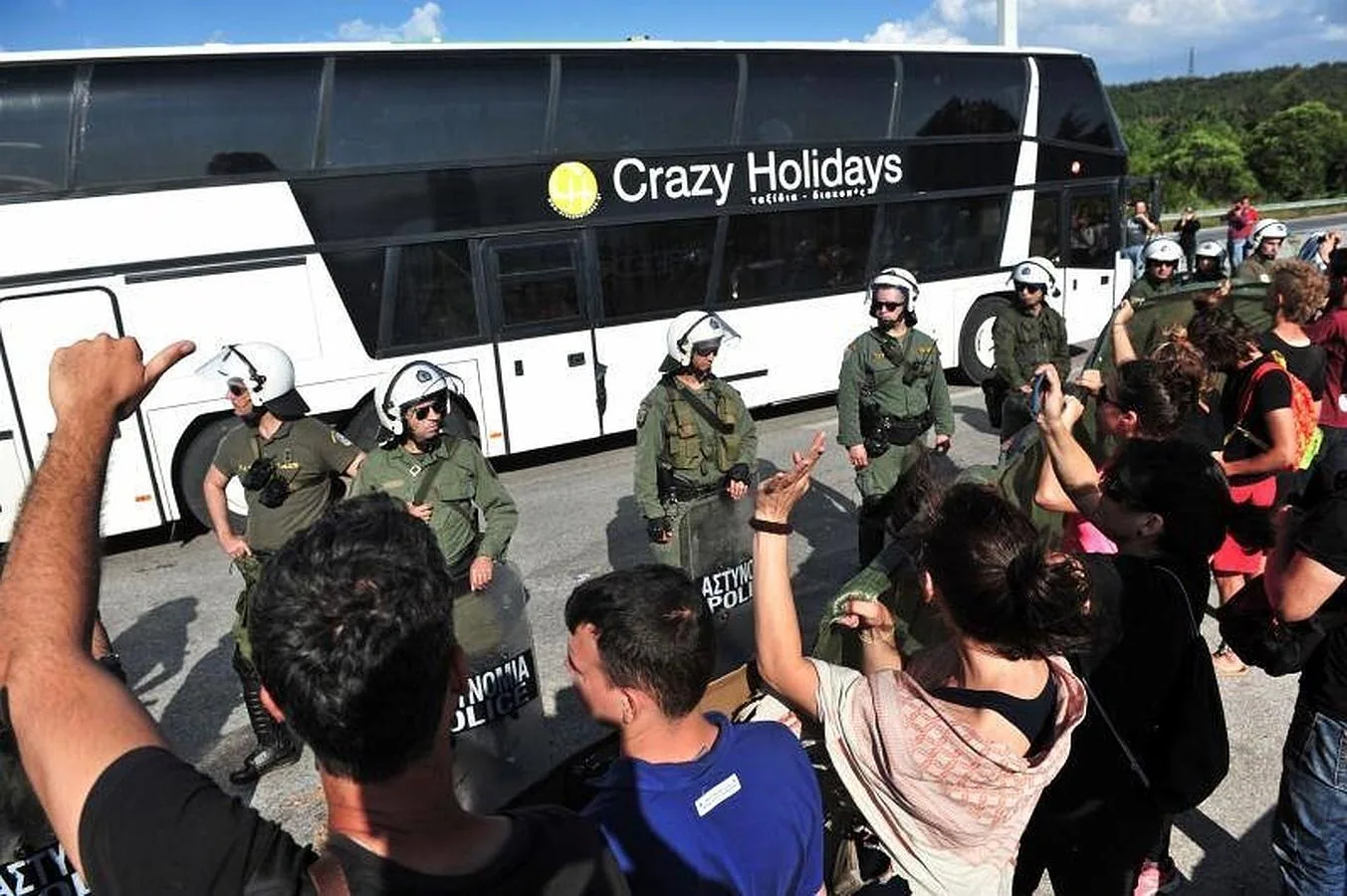 Una línea de policía antidisturbios montan guardia como grupos solidarios protestan la evacuación forzosa de migrantes y refugiados del campamento improvisado