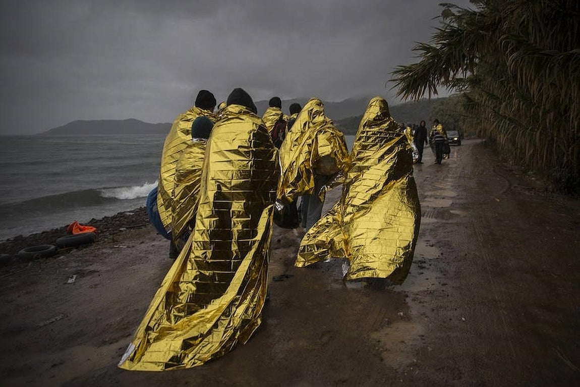 Un grupo de refugiados cubiertos con mantas térmicas abandona la playa de Skala Sikamineas a la que llegaron en patera, minutos antes, procedentes de las costas turcas. 