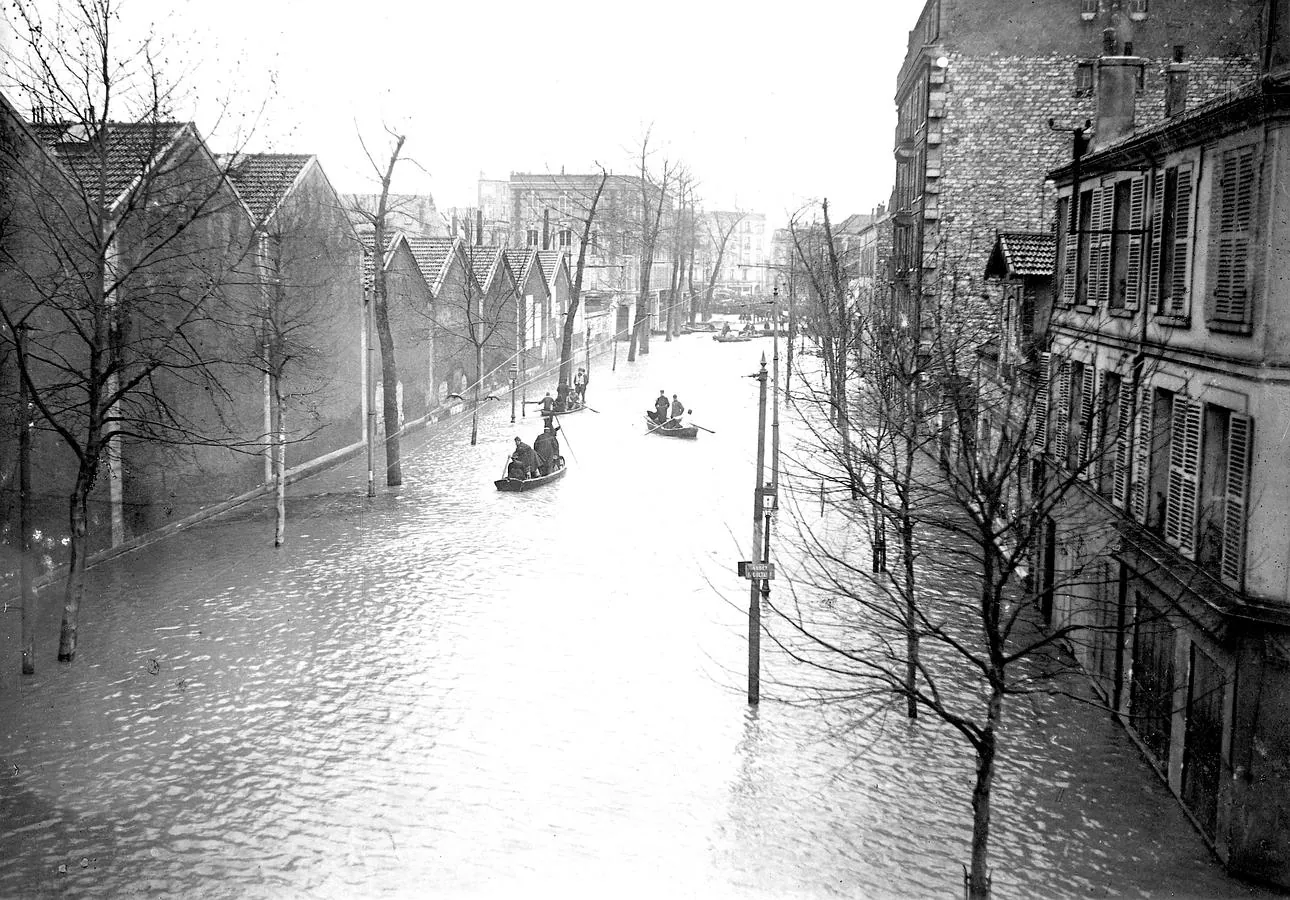 Un grupo de barcas atraviesan una calle inundada en 1910