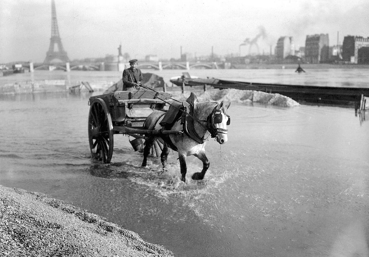Un hombre pasea con un coche de caballos en las calles inundadas de París en 1910