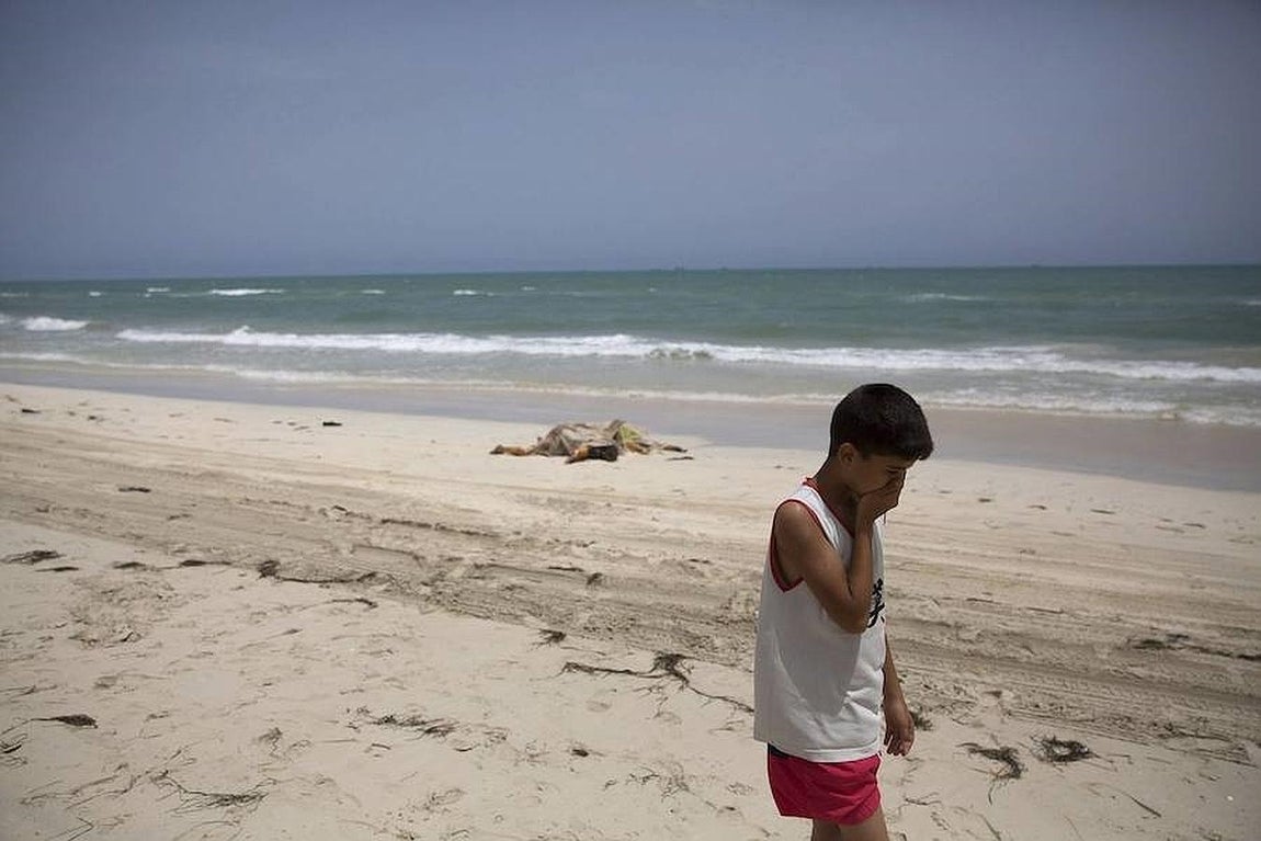 Un niño camina junto a los cuerpos sin vida de los inmigrantes que han aparecido en una playa de Zuwarah, al oeste de Trípoli (Libia), donde se han encontrado al menos 117 cadáveres este jueves. 
