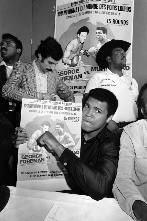 Esta foto de archivo tomada el 10 de septiembre, 1974 muestra a Muhammad Ali en París, durante una escala en su camino hacia Kinshasa, Zaire, que muestra el cartel del combate del campeonato del mundo de pesos pesados contra George Foreman, que finalmente se llevó a cabo el 30 de octubre de 1974. Ali ganó al noquear a Foreman en el octavo asalto. 