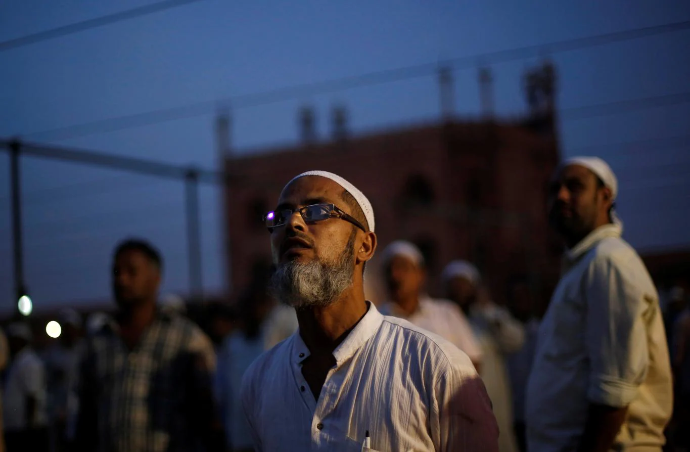 Unos musulmanes miran al cielo, en busca de la luna creciente, en la víspera del comienzo del mes sagrado del islam, este lunes en la gran mezquita de Delhi