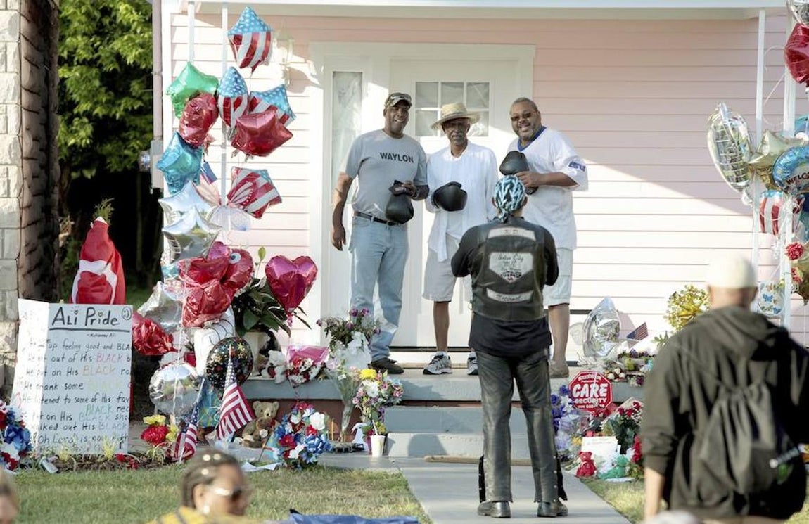 Varios seguidores posan con unos guantes delante de la casa de la infancia del legendario púgil. 