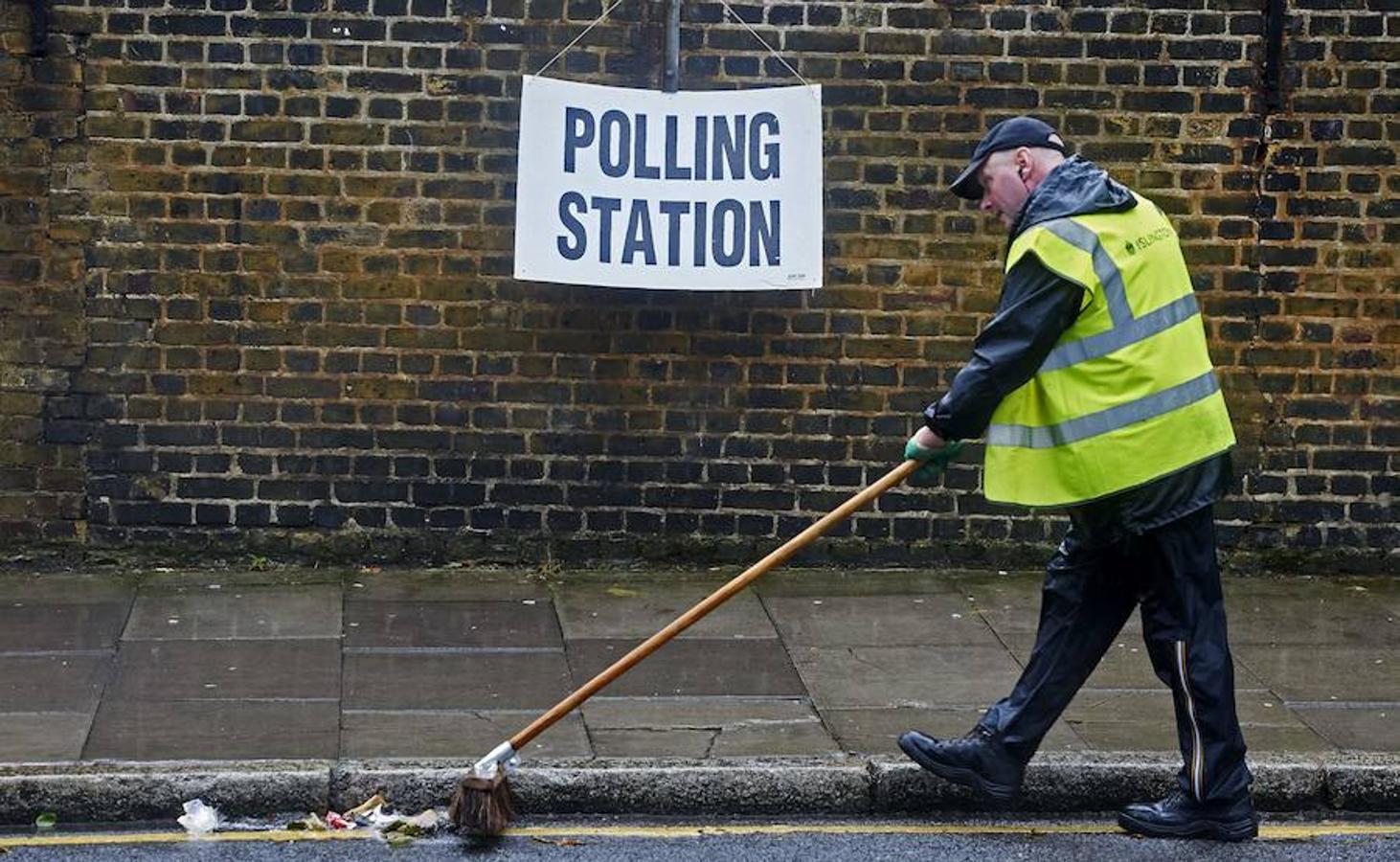 Un empleado barre las cercanías de un colegio electoral de Londres