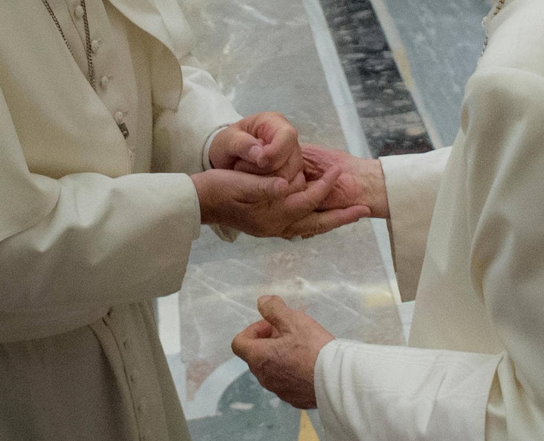 Momento en que el Papa Francisco y el Papa emérito ligan sus manos en el acto de homenaje al segundo en el 65 aniversario de su ordenación como sacerdote