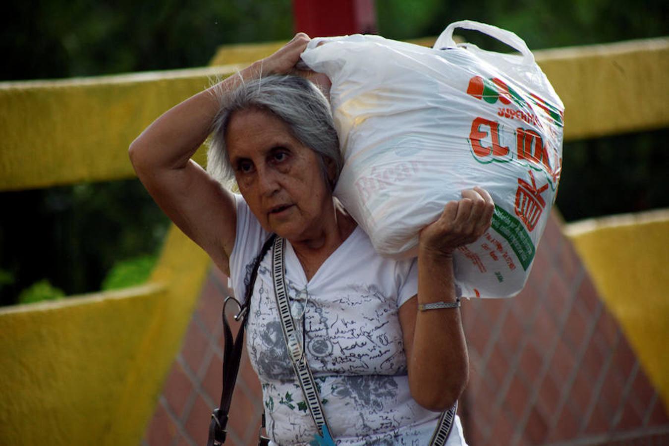 Una mujer carga una bolsa pesada tras comprar todo lo necesario para sobrevivir en Colombia. 