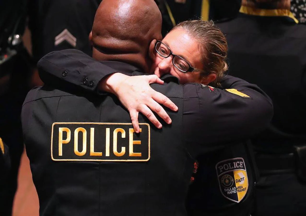 La oficial de policía Misty McBride abraza a un compañero justo antes de que empiece el funeral por los cinco agentes caídos durante la manza de Dallas