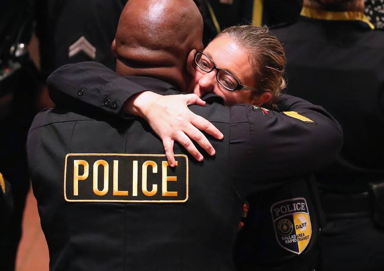 La oficial de policía Misty McBride abraza a un compañero justo antes de que empiece el funeral por los cinco agentes caídos durante la manza de Dallas. 