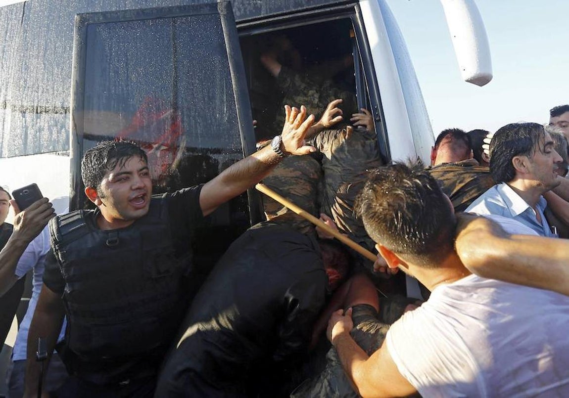 La policía protege a los golpistas de la multitud antes de ser detenido. 