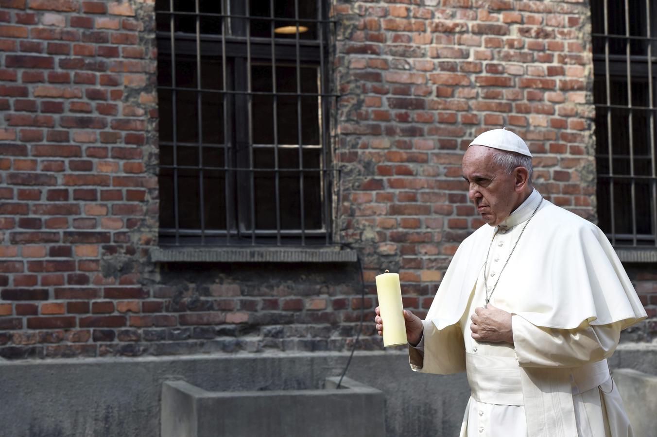 El Papa Francisco enciende una vela ante el «muro de la muerte». 