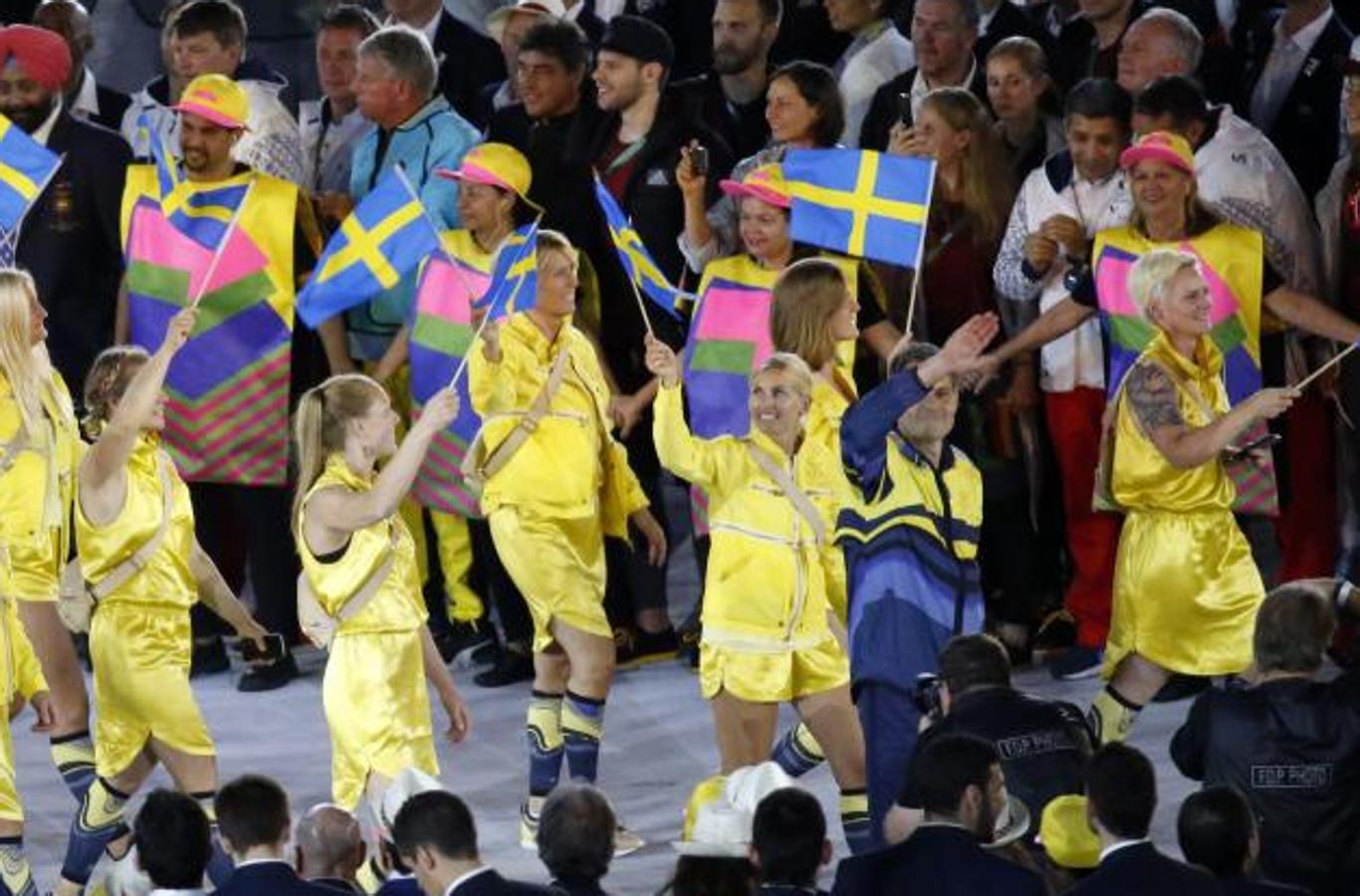 Grecia, los brillantes colores de su bandera. La delegación femenina griega lucía un atuendo formado por falda y chaqueta en un brillante color amarillo. Complementaban su conjunto con unas medias azules y una riñonera beige a la espalda.