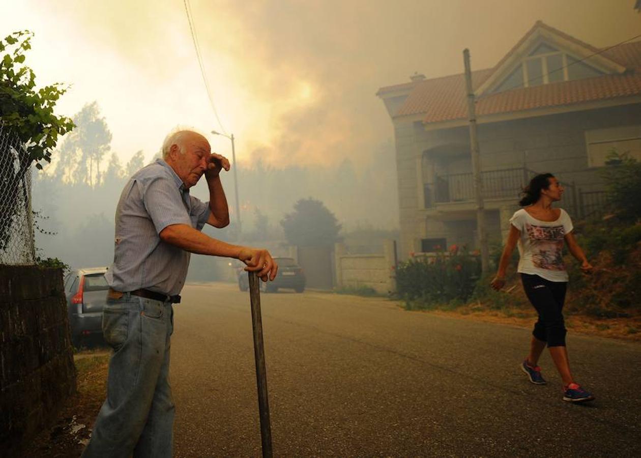 Un ciudadano de la localidad gallega pasea entre el humo provocado por el incendio