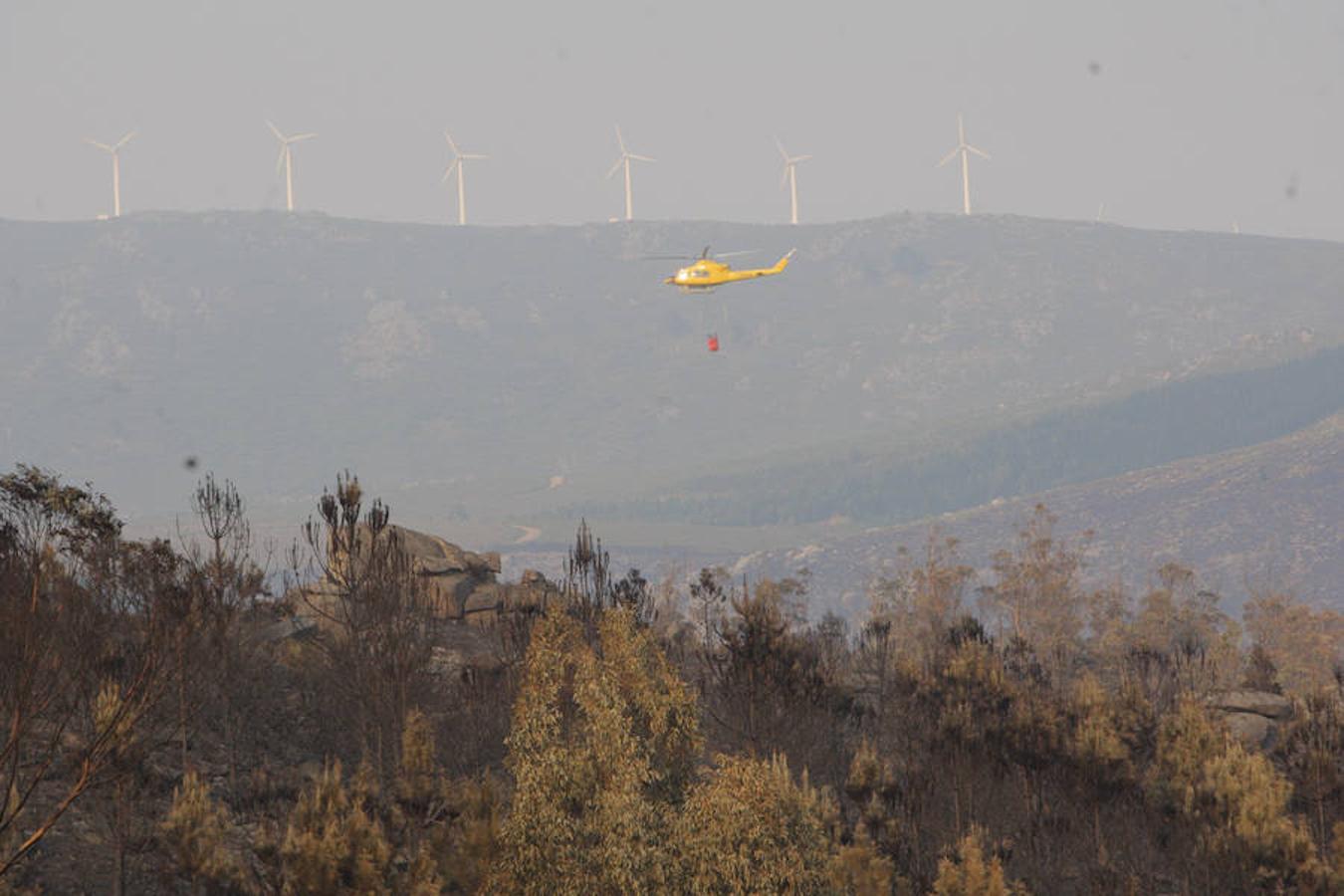 Un helicóptero trabaja en las labores de extinción del incendio en el municipio coruñés de Porto Do San, que ya ha calcinado más de 1.000 hectáreas. 