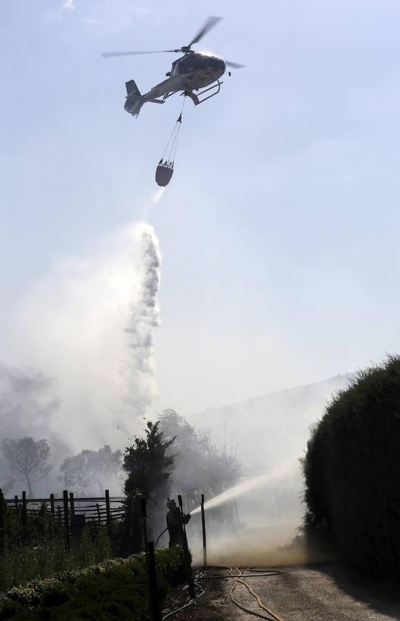 Un helicóptero y un bombero durante las labores de extinción de un incendio de vegetación que ha obligado a cortar esta tarde dos carreteras locales en las proximidades de Ororbia (Navarra). 