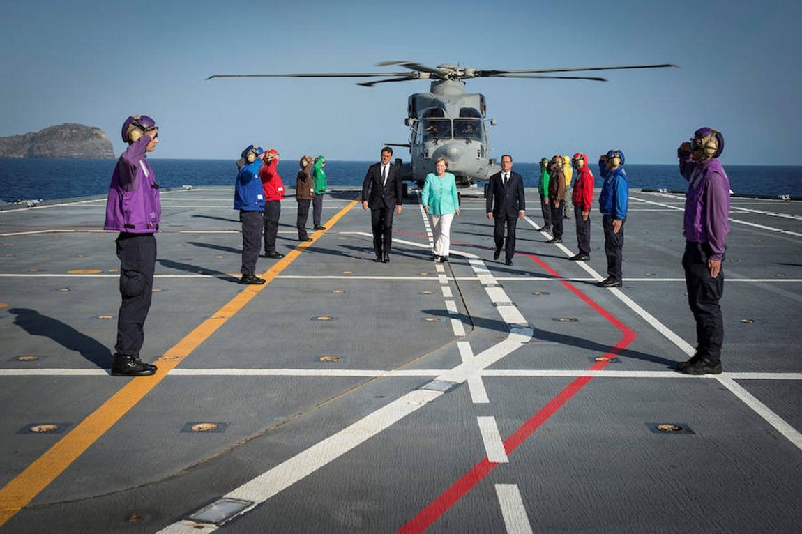 El primer ministro italiano, Matteo Renzi, la canciller alemana, Angela Merkel, y el presidente francés, Francois Hollande, llegan a una conferencia de prensa en el portaaviones italiano Garibaldi frente a la costa de la isla de Ventotene, el centro de Italia. 