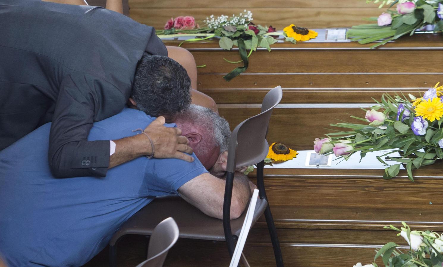 Dos hombres lloran sobre un ataúd durante el funeral celebrado en Ascoli Piceno. 
