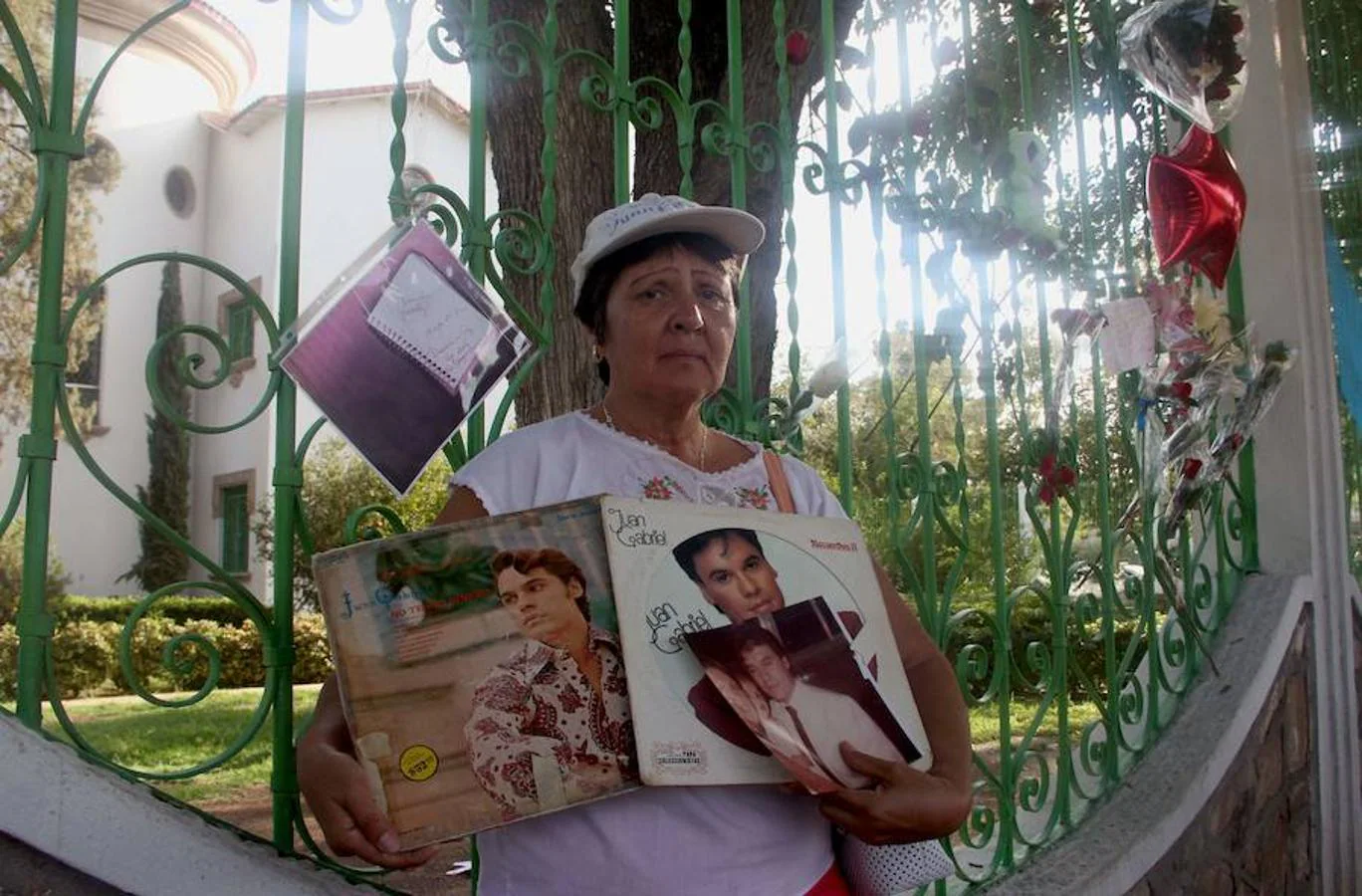 Una mujer posa con los álbumes del cantante junto a su domicilio
