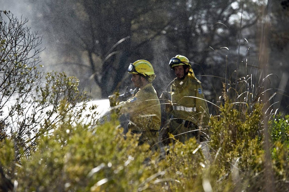 Efectivos del cuerpo de Bomberos durante las labores de extinción del incendio forestal que se ha declarado en la zona de Coves Noves, en Arenal d'en Castell, en el norte de Menorca, y que ha obligado a desalojar a cerca de 600 personas que viven en estos núcleos residenciales del municipio de Es Mercadal. 