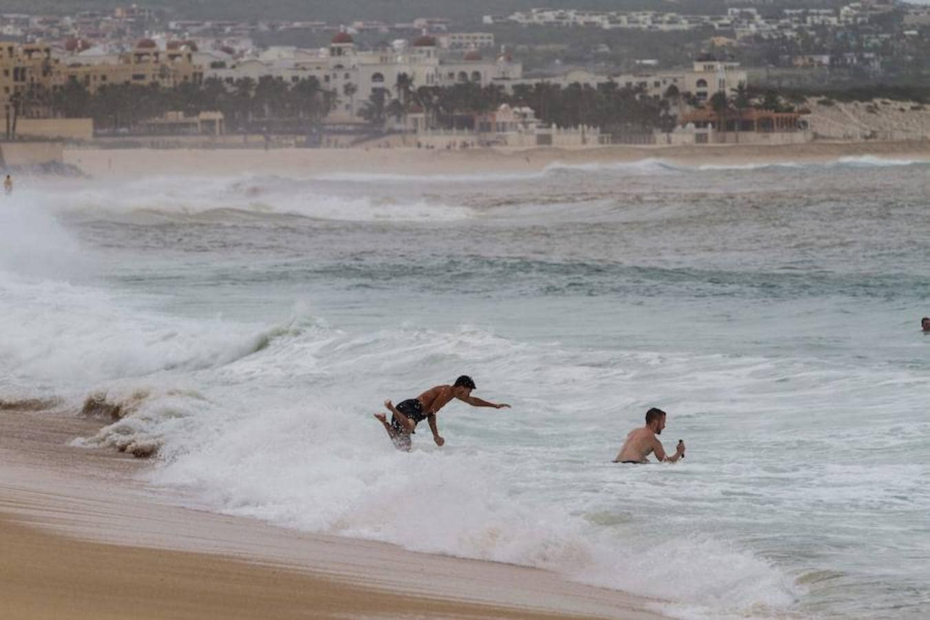 Turistas que juegan en una playa de Los Cabos (México) en plena tormenta