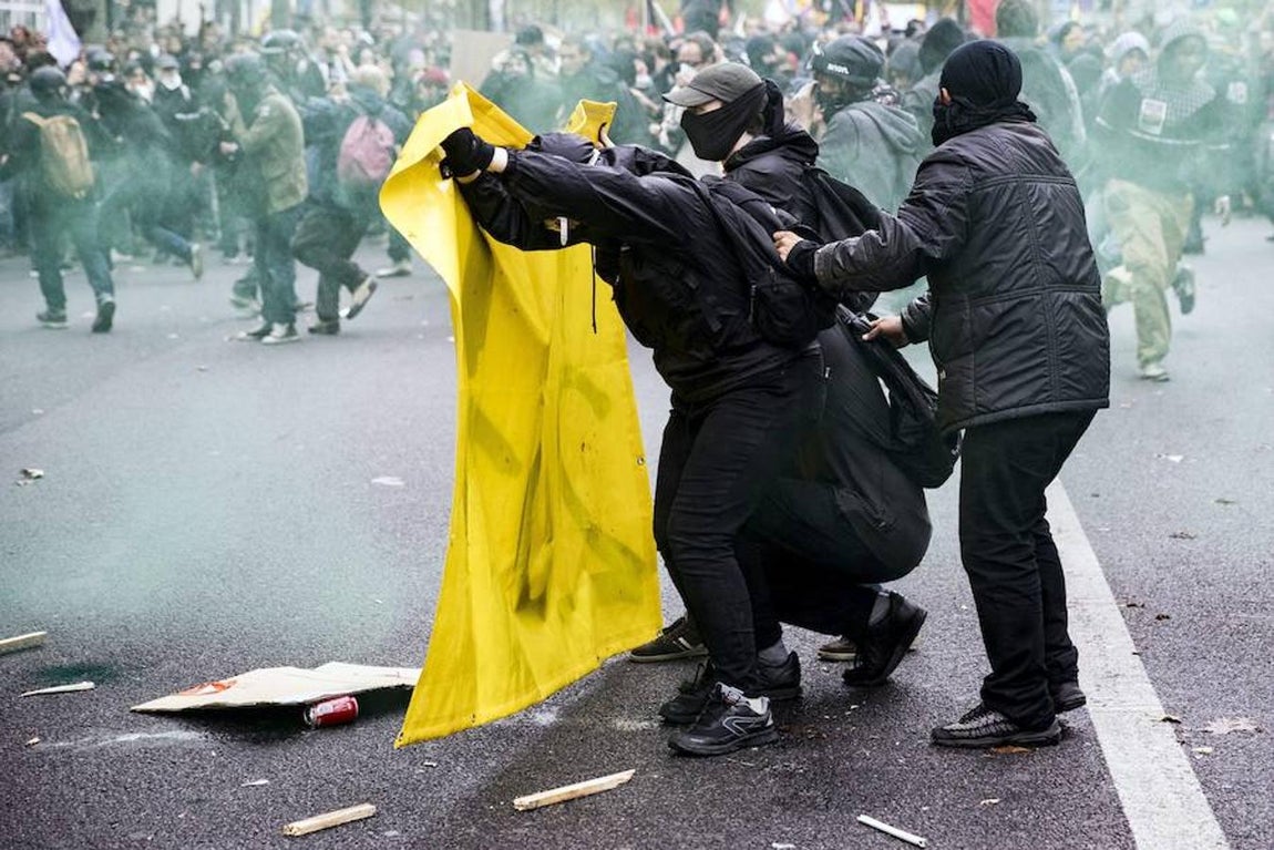 Tres manifestantes se protegen detrás de una pancarta de los ataques por parte de los policías. 