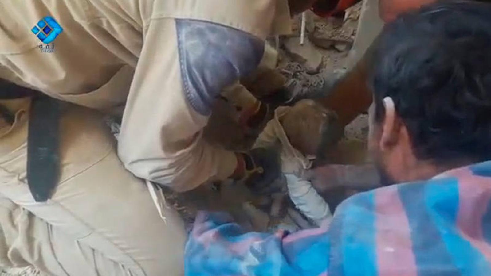 Voluntarios de protección civil de Siria, conocidos como los Cascos Blancos, recuperan cuerpos de entre los escombros de un edificio tras un ataque aéreo. 