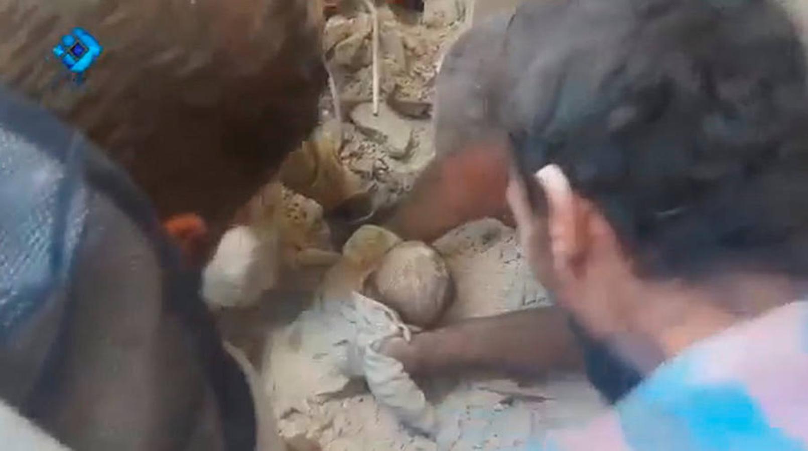 Voluntarios de protección civil de Siria, conocidos como los Cascos Blancos, recuperan cuerpos de entre los escombros de un edificio tras un ataque aéreo 