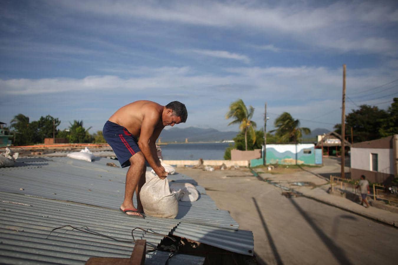 En Cuba, un hombre pone bolsas de piedras en el techo de su casa para evitar que el Huracán Matthew lo arranque