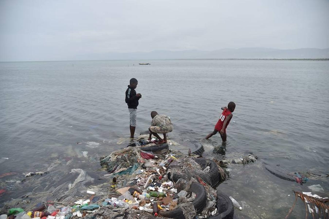 Niños juegan con la basura arrastrada por el huracán hacia la playa en Haití