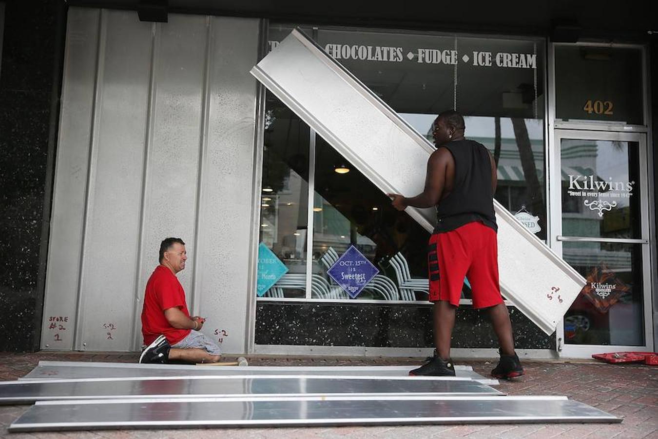 Dos hombres protegen el exterior de una tienda en Delray Beach, Estados Unidos, antes de que llegue Matthew. 