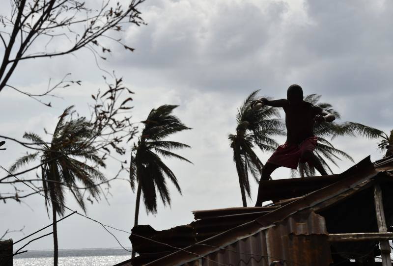 Un hombre trata de arreglar un tejado tras el paso del huracán Matthew