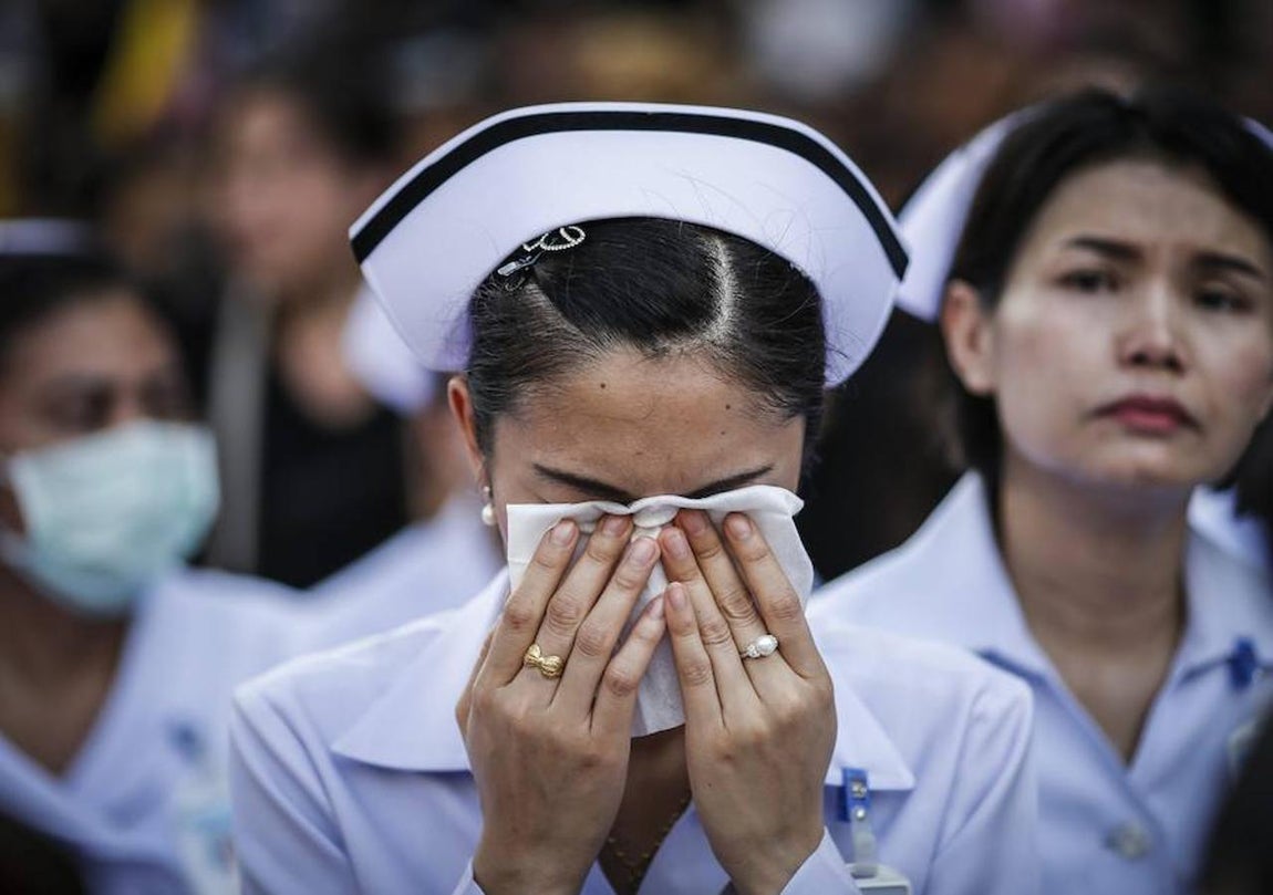 Una joven llora durante la procesión del féretro con los restos mortales del retrato del Rey Bhumibol de Tailandia desde el hospital de Bangkok. Efe