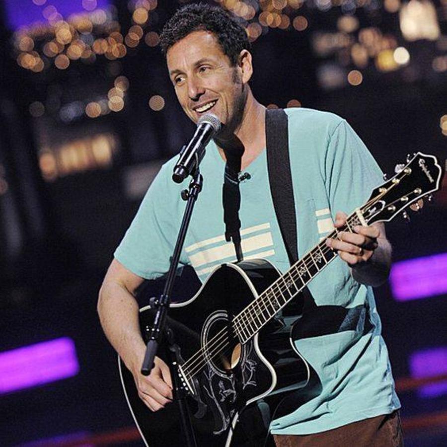 Adam Sandler toca la guitarra. 