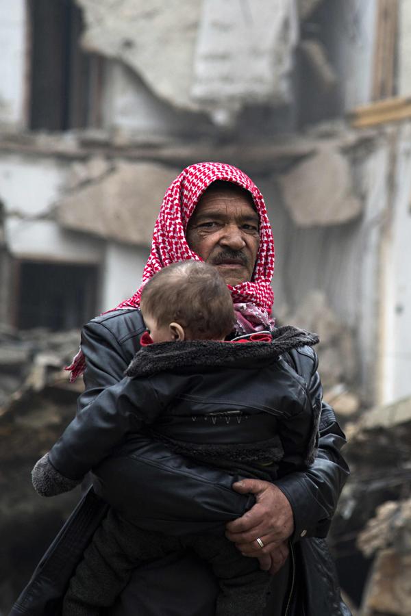 Un hombre deja un barrio del este de Alepo con un niño en brazos. 