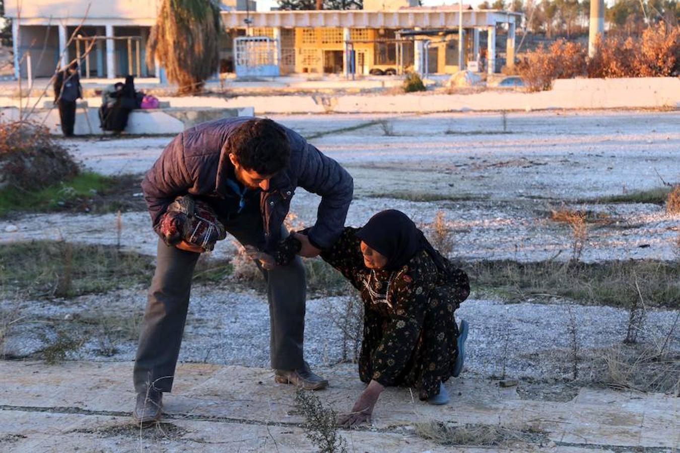 Un hombre ayuda a una mujer a levantarse durante la evacuación del este de Alepo.