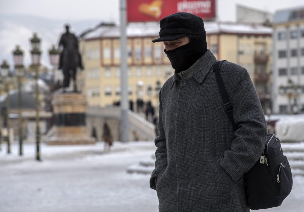 Un hombre camina con el rostro cubierto para evitar el frío en Skopje, Macedonia