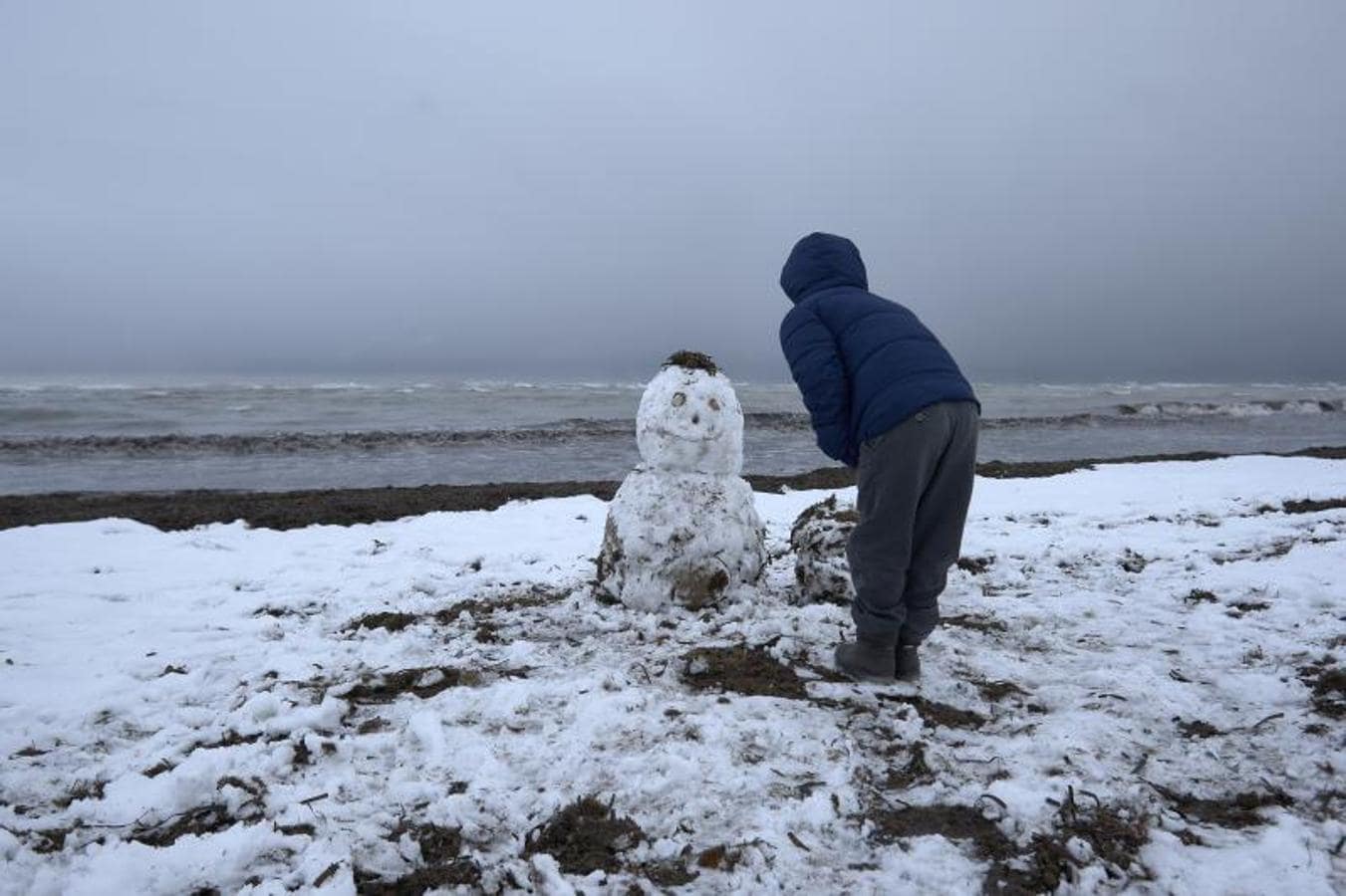 La ola de frío deja estampas insólitas, como la de este niño haciendo un muñeco de nieve en la playa de Denia