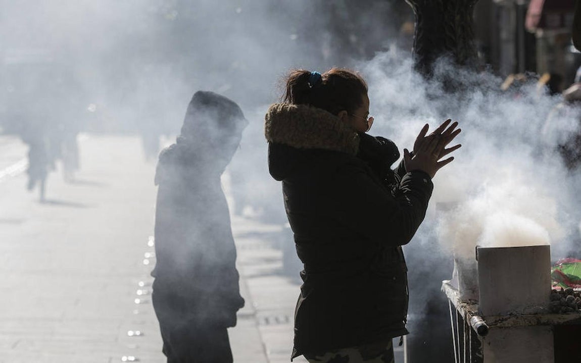 Las imágenes más impactantes de la ola de frío. Hay que calentarse de cualquier forma: una castañera de Sevilla no se separa de su kiosco.