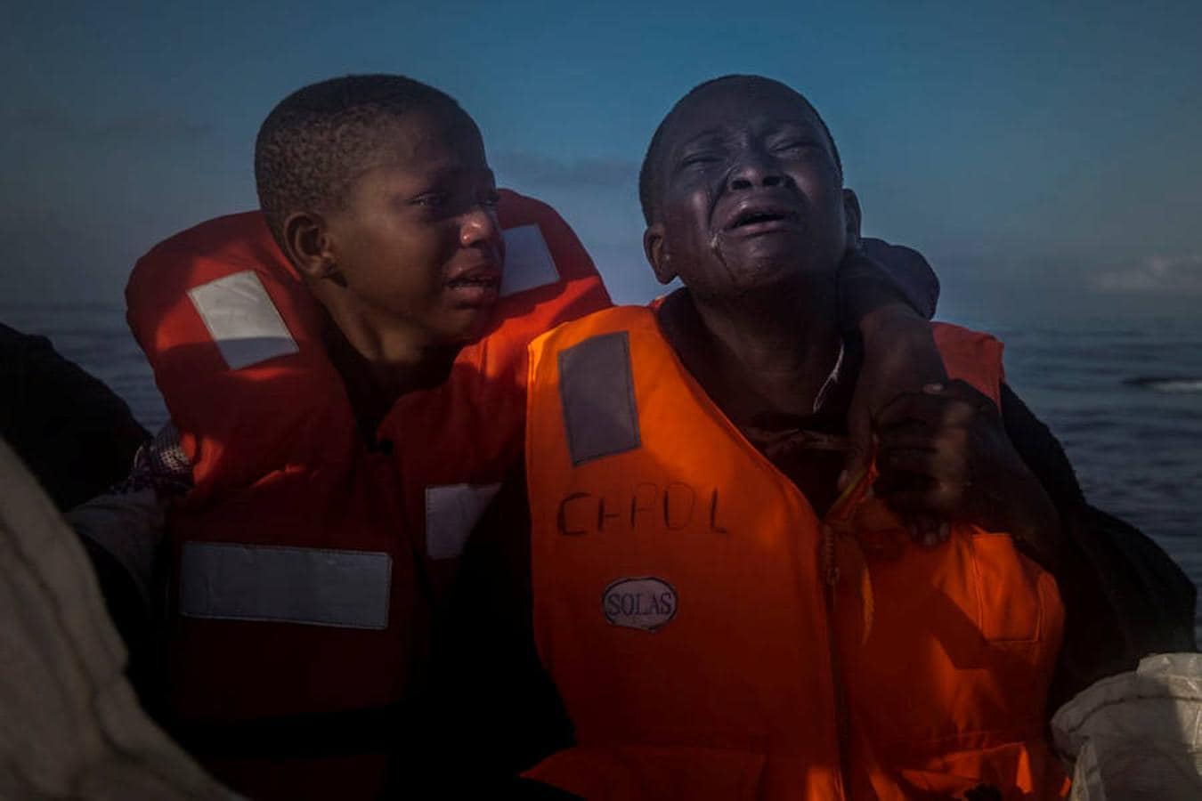 Una niña de 11 años de Nigeria (a la izquierda), quien dijo que su madre murió en Libia, llora junto a su hermano de 10 años a bordo de un barco de rescate de una ONG