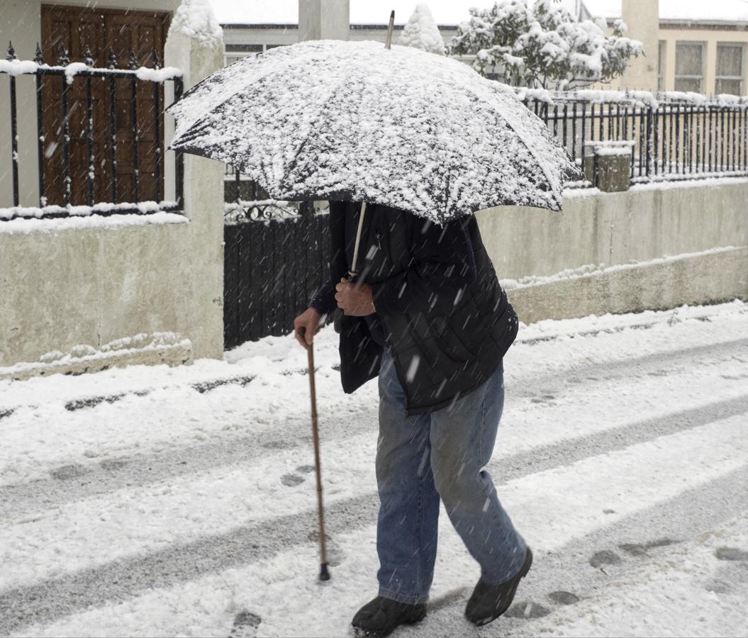 Un hombre se protege de la nieve en el municipio de Palas de Rei (Lugo)