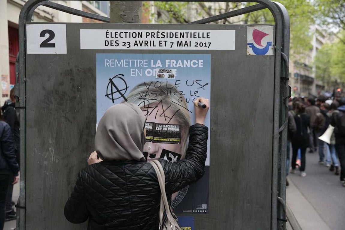 Una muanifestante pinta un cartel propagandístico de Le Pen. 