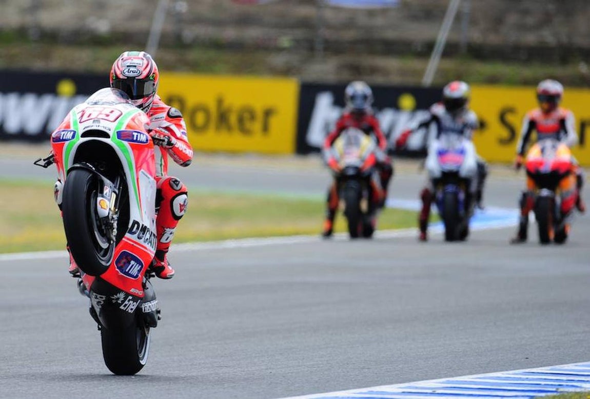 Nicky Hayden, uno de los pilotos con mayor sentido del espectáculo que había en el paddock, realiza un caballito ante la atenta mirada de Pedrosa y Lorenzo en el GP de Jerez 2012. AFP