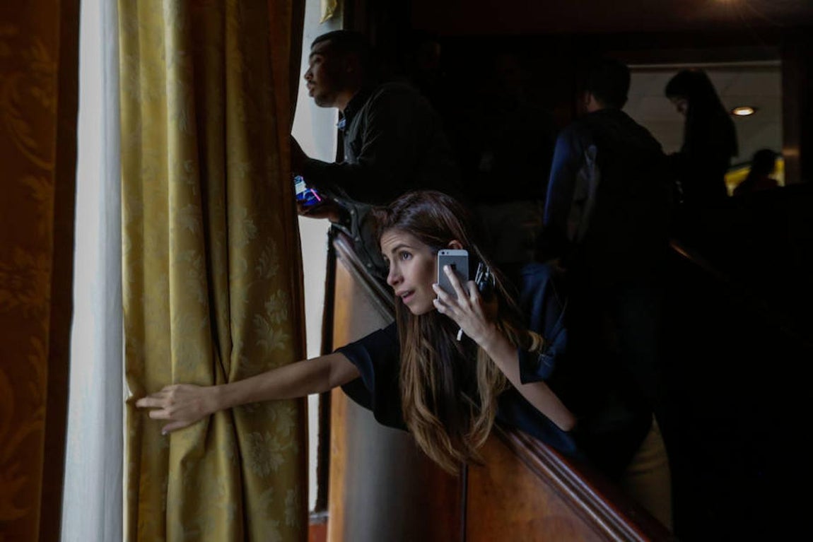 Periodistas observan a través de ventanas a simpatizantes oficialistas que se concentran en las afueras de la Asamblea Nacional.. 