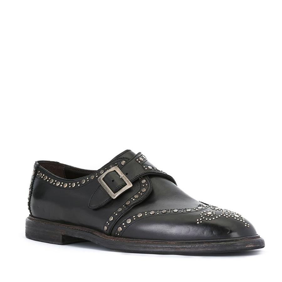 Zapatos monk en piel de becerro color negro adornados con tachuelas grises (845 €).