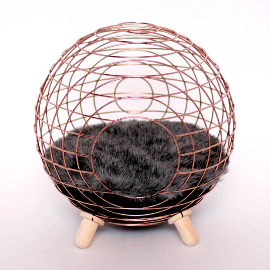 Gold Borbón Throne, de Lord Paw. Dentro de esta esfera el felino descansará como un rey. Su estructura, original y discreta, consigue que no desentone en ningún rincón. Tiene dos patas de madera y sobre ellas reposa la esfera metálica, dentro de ella el gato encontrará una elegante manta de piel artificial.  Su precio es de 227,57 euros.