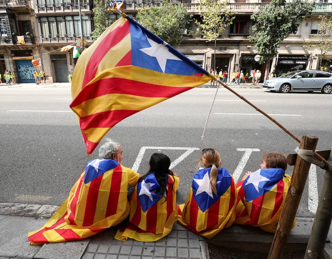 Un grupo de personas sentadas en la calle cubiertas con la Estelada. 